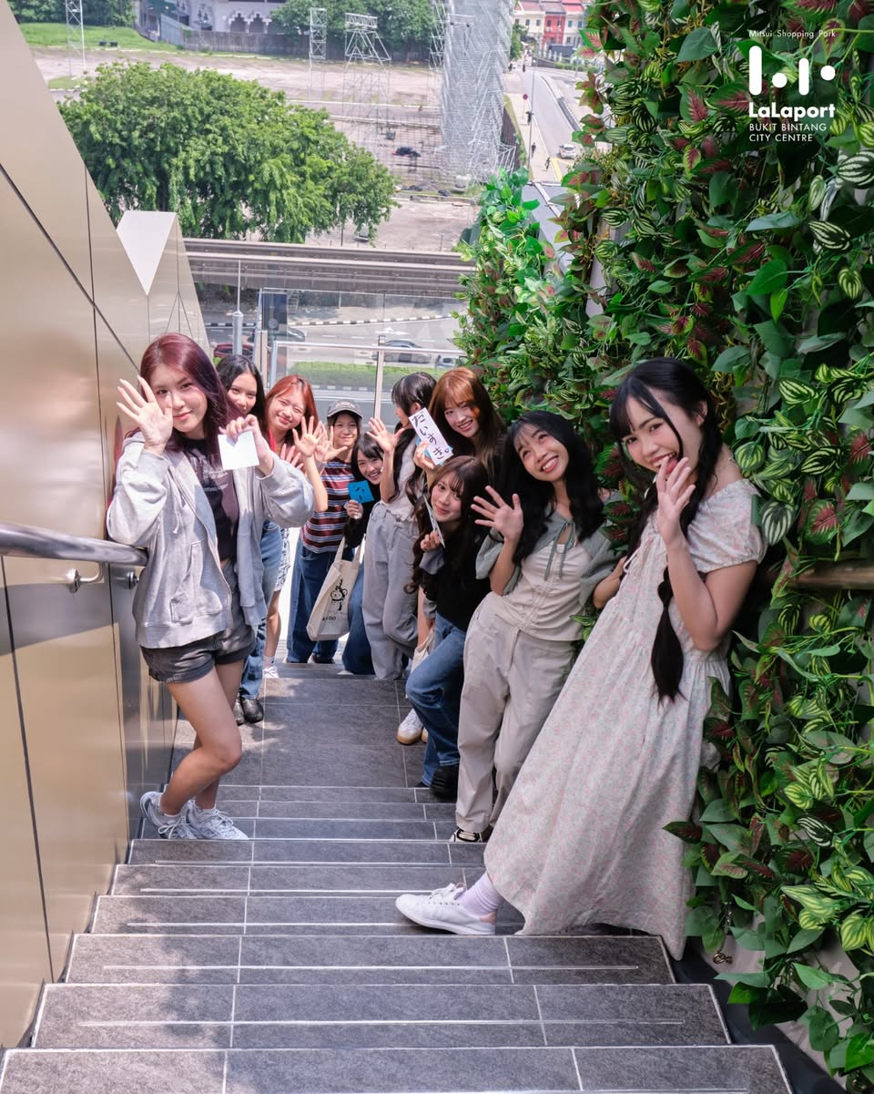 Group of visitors posing on outdoor stone steps near LaLaport East and West