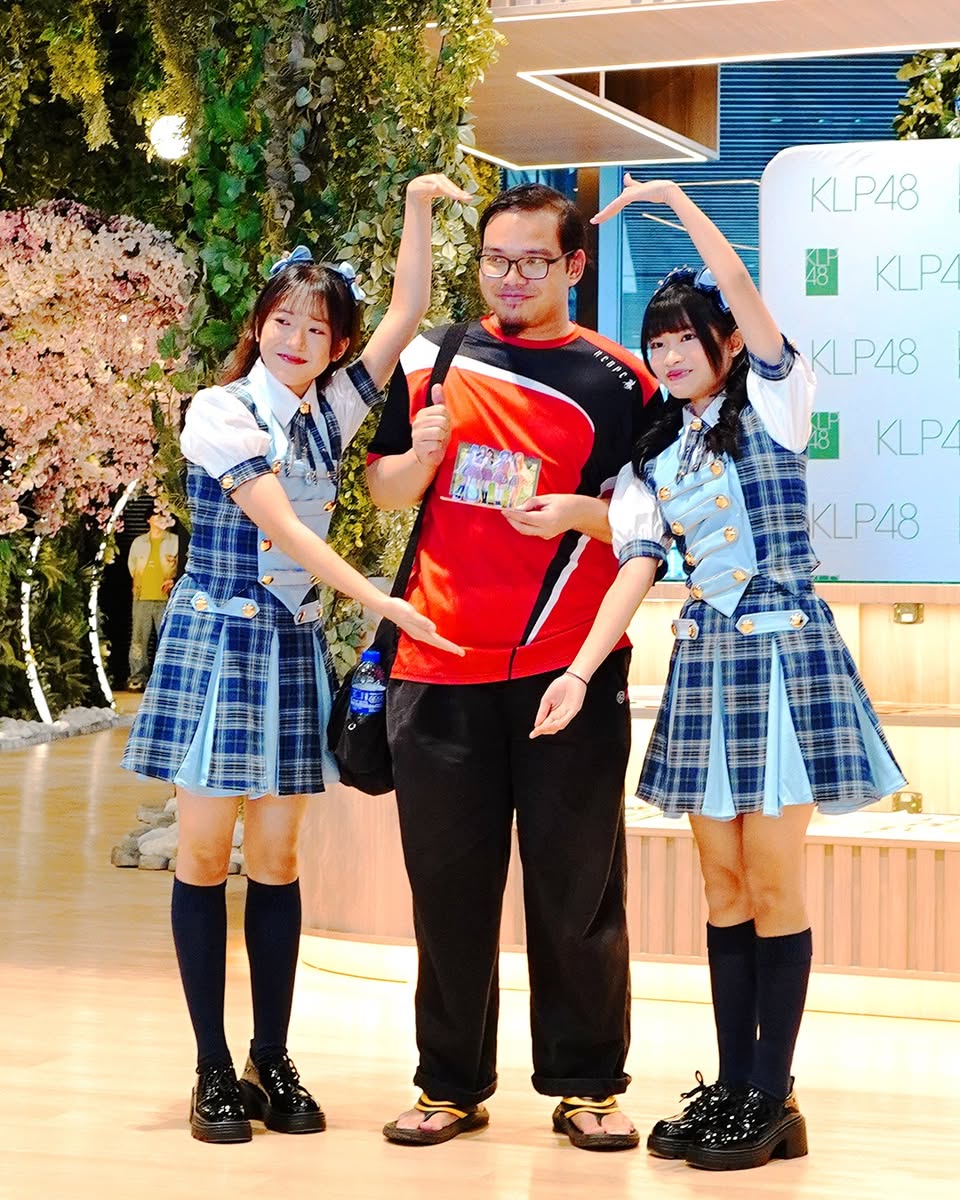 KLP48 members posing with a life-sized standee prize.